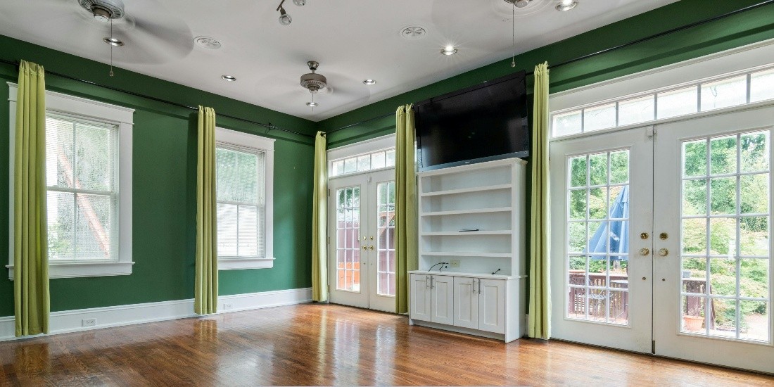 Bright living room with green walls, hardwood floors, and French doors highlighting replacement windows and doors in Portland, OR