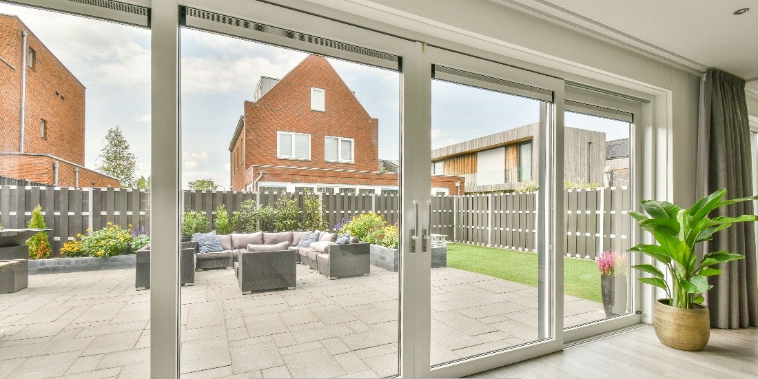 Modern home patio with large glass sliding doors showcasing replacement windows and doors in Portland, OR, opening to a landscaped backyard with outdoor seating