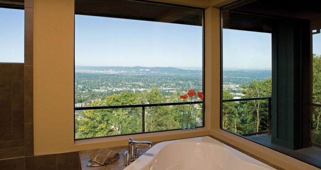 Large picture windows overlook a scenic hillside and city view from a bathroom in Tigard, OR. Select 84 more words to run Humanizer.